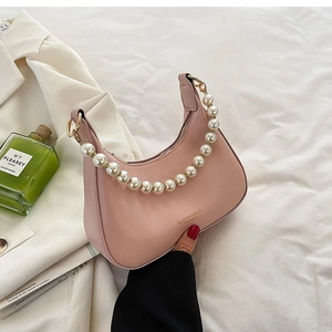 Détail du sac à bandoulière rose en cuir avec anse décorative en perles et finitions dorées