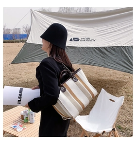 Détail d'un sac seau en toile rayée avec garniture en cuir et bandoulière chaîne en plein air