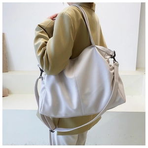 Detail of creamy white faux leather tote with litchi grain and black metal hooks