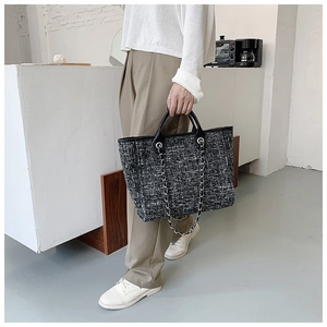 Detail showing high-capacity black and white tweed tote bag with elegant silver metal chain