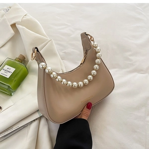 Détail du sac croissant en cuir avec une élégante poignée en chaîne de perles blanches