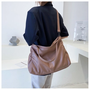 Brown large PU leather shoulder bag shown on model against a minimalist white background