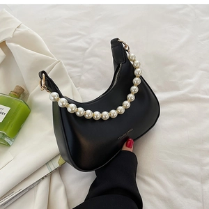 Détail du sac croissant noir avec poignée de perles élégante et texture cuir lisse