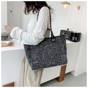 Detail of tweed tote bag with black leather trim and metal chain strap for women