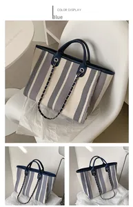 Detail of navy blue and white striped tote bag with chain strap and leather trim accents