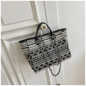 Detail of bohemian canvas tote bag with geometric patterns and metal chain strap