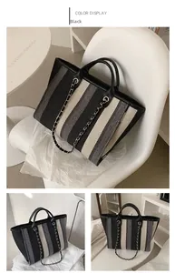 Detail view of large striped canvas tote bag with chain strap and handle in black and grey