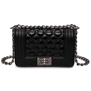 Detailed shot of black quilted crossbody bag with gunmetal chain strap and metal lock