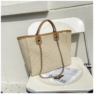 Detail of woven bucket bag with geometric patterns, leather trim and metal chain strap