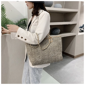 Model wearing a large capacity tweed tote bag with metal chain strap in modern interior
