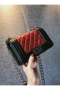 Detail of red and black quilted leather crossbody bag with heavy metal chain strap