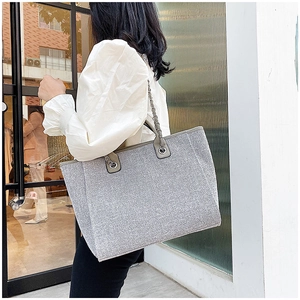 Detail of silver glitter tote bag showing metallic chain strap and shimmering fabric texture