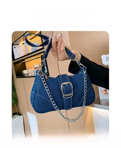 Deep blue denim shoulder bag featuring contrast white stitching and large metal buckle