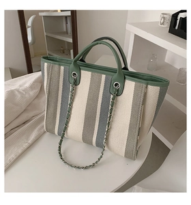 Détail du sac cabas tissé à rayures avec finitions en cuir vert et bandoulière chaîne