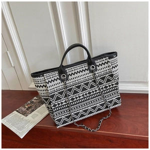 Detail of tribal pattern woven bucket bag with leather handles and chain strap