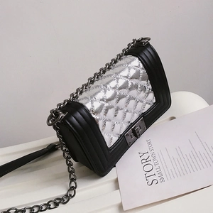 Detail of silver metallic quilted panel and chain strap on small square crossbody bag