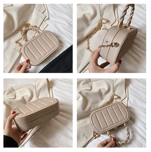 Detail of beige oval box bag featuring vertical stripes, twist handle and gold chain
