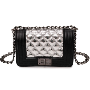 Detail of quilted silver panel with metallic push-lock and chain strap on crossbody bag