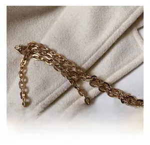 Detailed close-up of polished gold chain link strap on textured cream fabric background