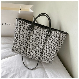 Detail of black and white geometric patterned tote with chain strap and leather handle