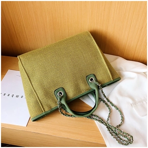 Detailed view of green woven tote bag texture with silver chain and green leather strap