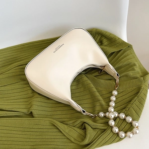 Sac sous le bras en cuir crème avec grosse chaîne de perles et fermeture sur tissu vert