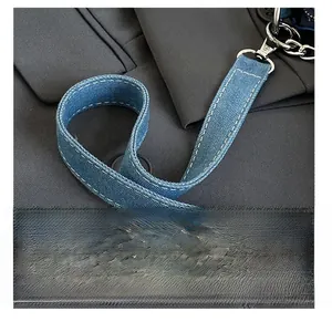 Detail view of blue denim fabric texture with white contrast stitching and metal hardware