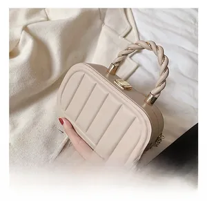 Close-up of beige crossbody bag with striped texture, twisted handle and gold clasp