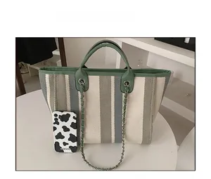 Detailed size comparison of the large striped canvas tote bag next to a mobile phone