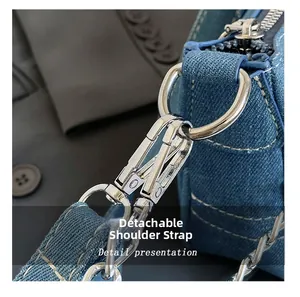 Detail of detachable denim strap with silver metal spring buckle and D-ring connector