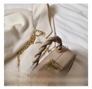 Detail of beige quilted leather bag with twisted handle and gold chain shoulder strap