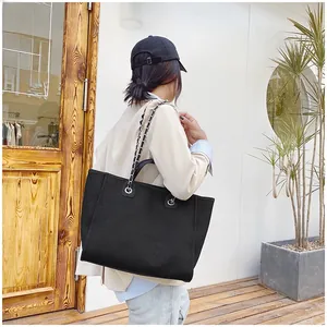 Street style shot of a black large capacity tote bag with silver chain straps and leather handles