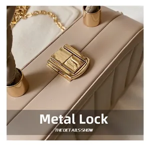 Macro view of gold metal lock and vertical pleated texture on beige leather bag