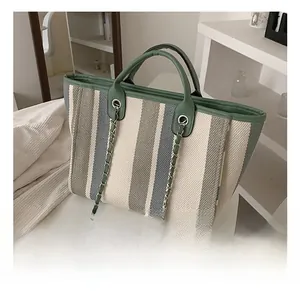 Detail of green and white striped tote bag with leather handles and silver chain link
