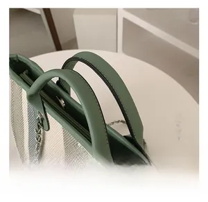 Detail of green and white striped canvas tote bag showing soft leather handle and metal chain