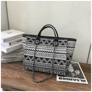 Detail of black and white geometric jacquard bucket bag with leather handle and chain