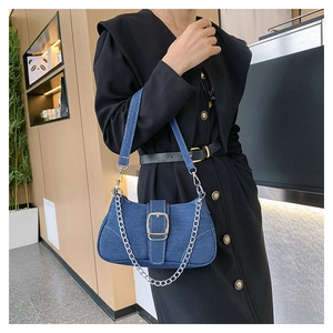 Close-up of denim texture crossbody bag with silver chain strap and metallic buckle