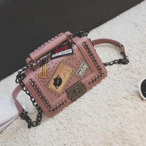 Pink structured crossbody bag with woven handle, black metal chain, and punk patches