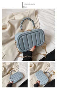 Detail of blue box bag showing vertical quilted texture, braided handle and gold chain strap