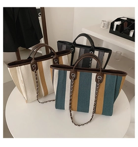 Close-up of three striped canvas tote bags with leather handles and silver chain straps