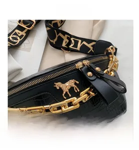 Detail of crocodile embossed crossbody bag with chunky gold chain and horse logo
