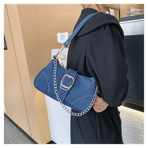 Close-up of blue denim crossbody bag with silver chain detail and sleek shoulder strap