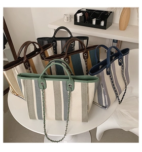 Close-up of five colorful striped canvas tote bags with leather handles and chain straps