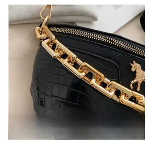 Close-up of black crocodile texture bag with chunky gold chain and horse emblem