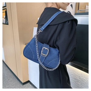 Detail of denim blue crossbody bag with white stitching and silver metal buckle