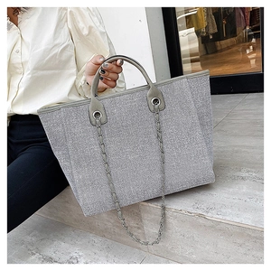 Detail view of large silver glitter tote bag with chain straps and top handles