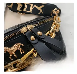 Detail of smooth metal zipper and golden horse emblem on black crocodile embossed bag