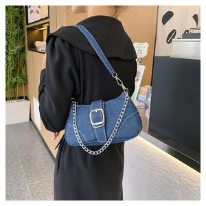 Detail view of denim crossbody bag with large metal buckle and silver chain strap