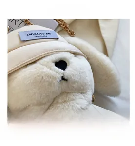 Détail du sac en peluche lapin blanc avec chaîne dorée et étiquette de la marque