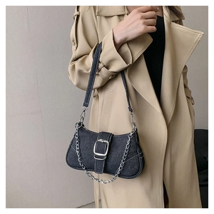 Detail of black denim texture bag with metallic chain and silver buckle closure